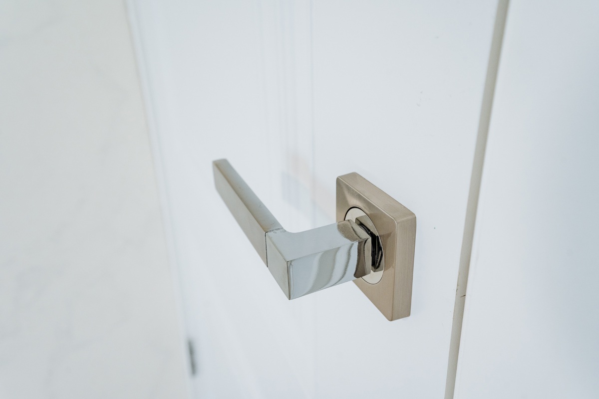 This image features a closeup view of a door handle positioned prominently on a freshly painted white door