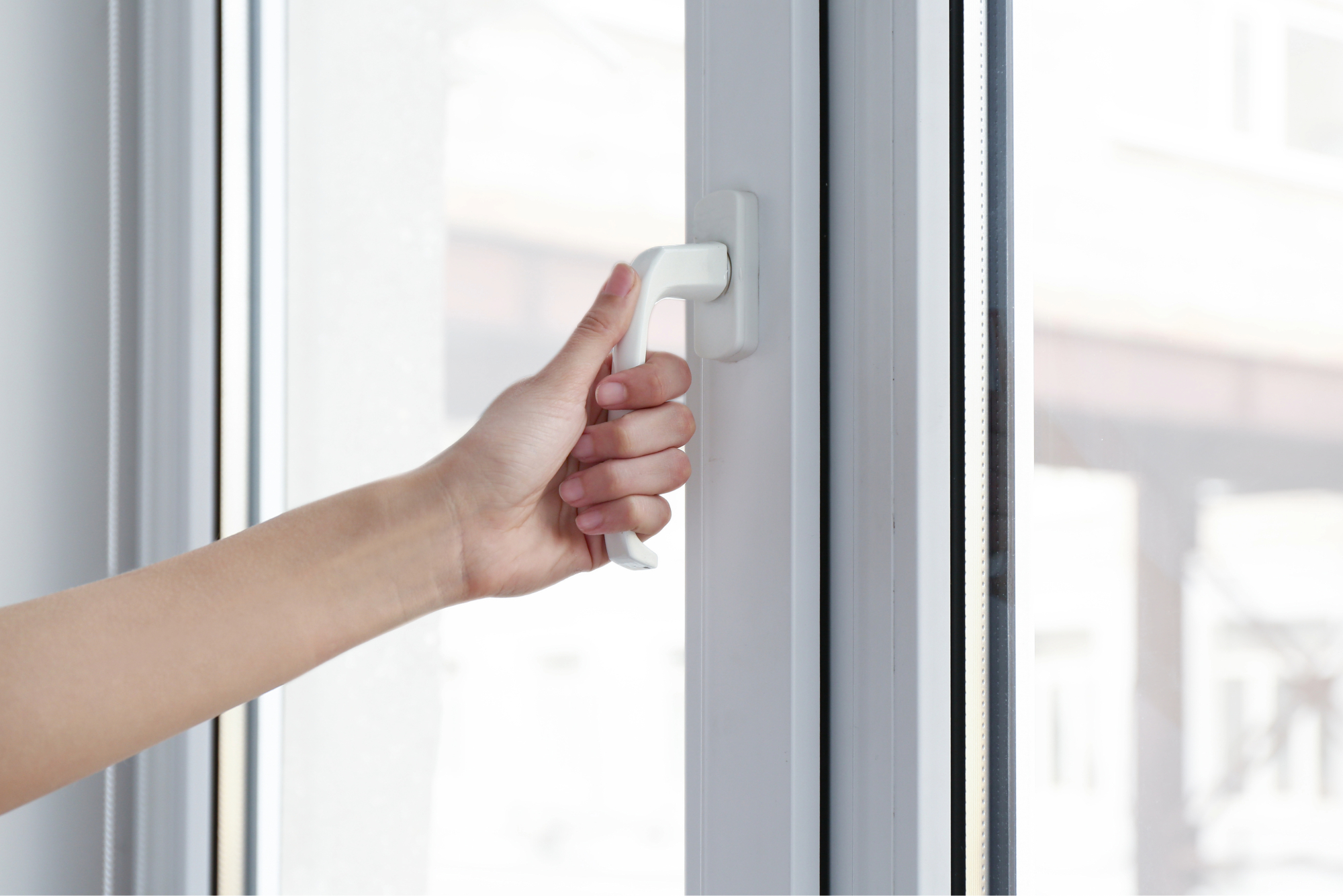 A white handle on a white uPVC window being opened by a hand