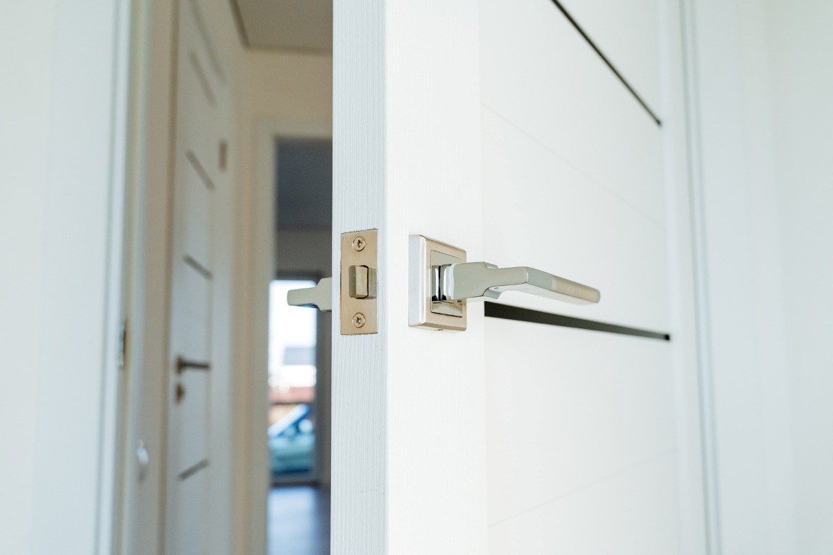 An ajar door in the room, a built-in door lock, chrome decor elements in the interior of the apartment.