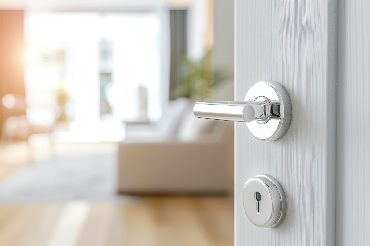 Doorknob. Metal door handle lock and latch of brass on veneer doors. Door wooden half opening through interior bedroom background, selective focus. Modern trends in interior design. 